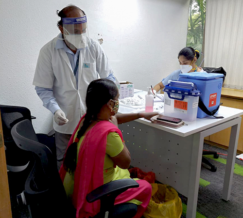man wearing a black jacket, white shirt, blue jeans, and brown boots, playing a white electric guitar while sitting on an amp