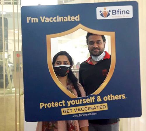 man wearing a black jacket, white shirt, blue jeans, and brown boots, playing a white electric guitar while sitting on an amp