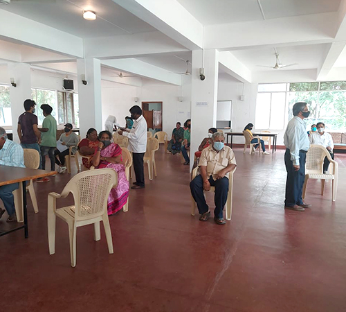 man wearing a black jacket, white shirt, blue jeans, and brown boots, playing a white electric guitar while sitting on an amp